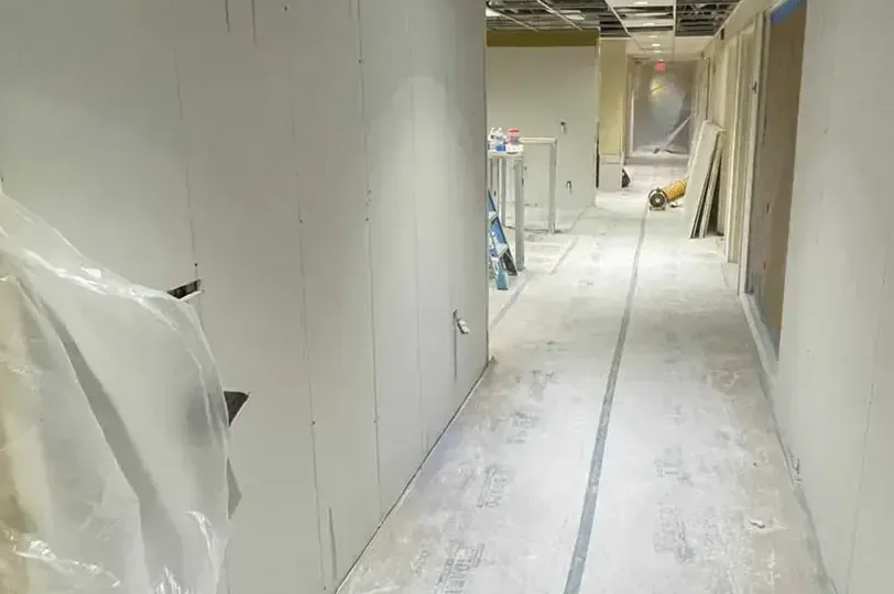 Plastic containment and opened wall bottoms along a hallway during structural drying