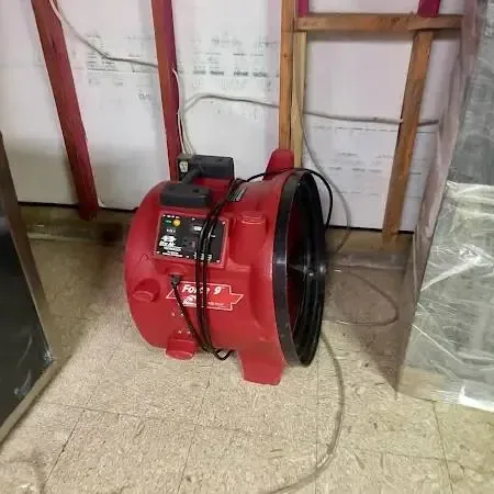 A red air mover, hung plastic sheeting and an opened lower wall during a Marietta water damage dry-out