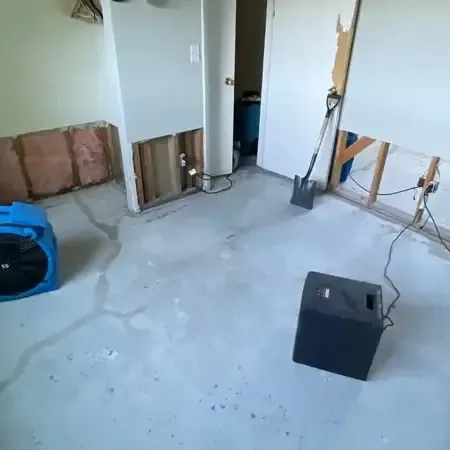 Air movers and a dehumidifier drying a room in Mableton with the lower drywall removed