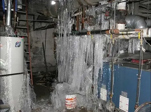 Ice coating the pipes in a basement utility room after a hard freeze