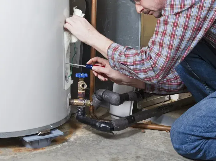 A homeowner checking the valves and the wet base of a leaking water heater